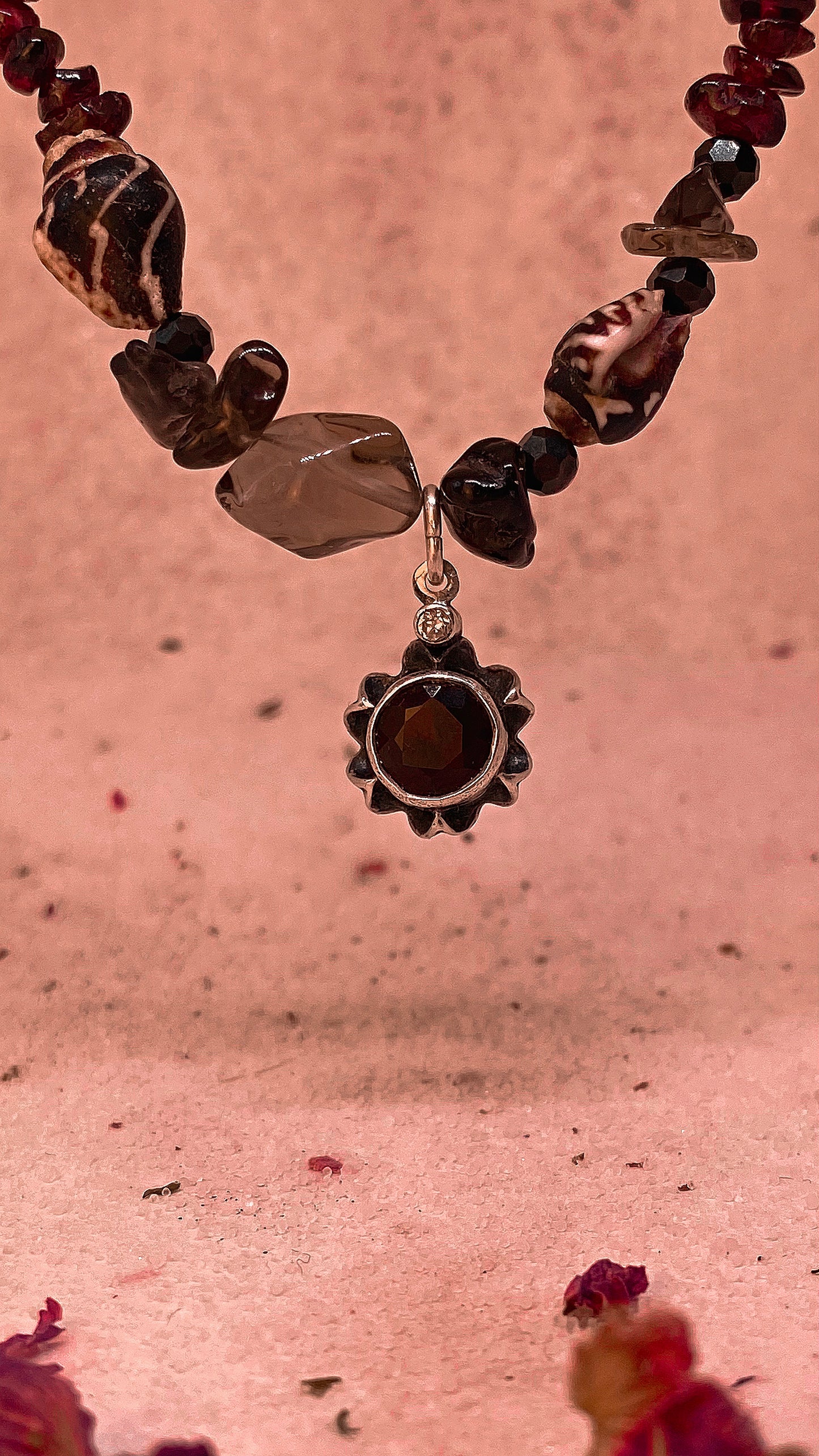 faceted garnet flower on textured garnet, seashell, glass