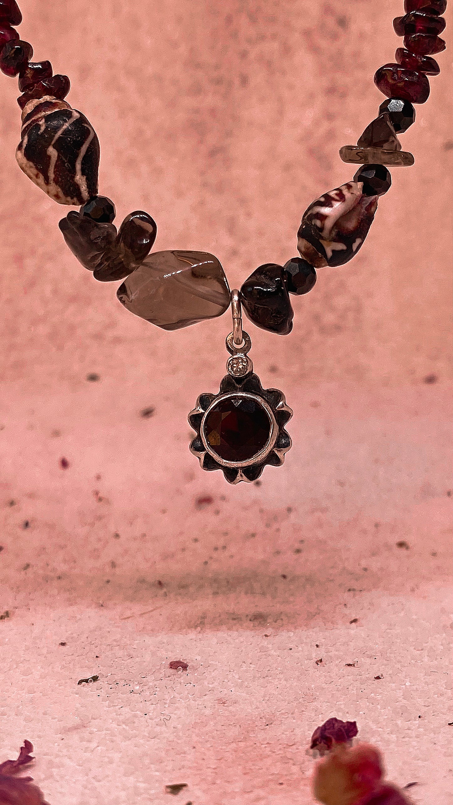 faceted garnet flower on textured garnet, seashell, glass
