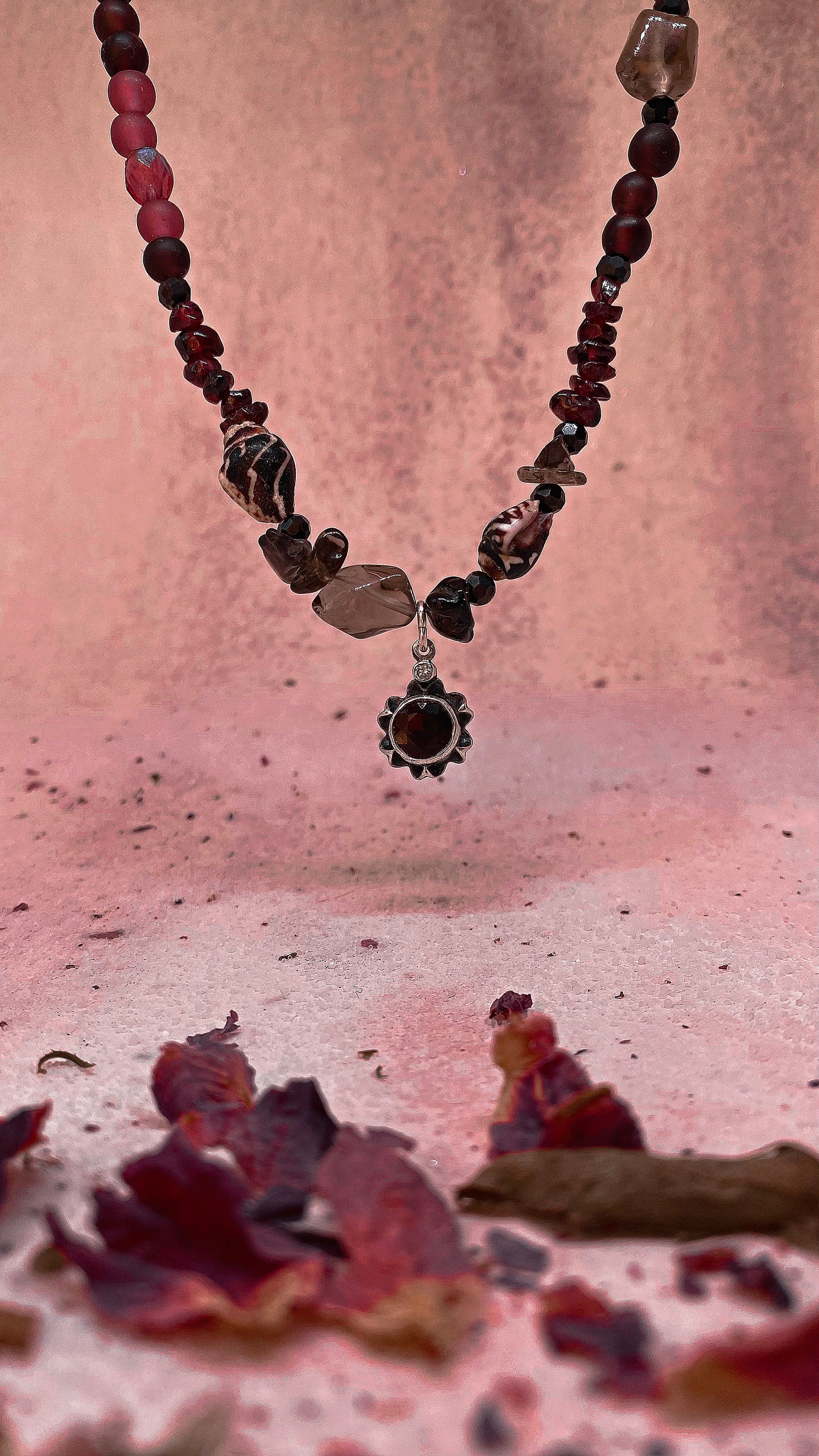 faceted garnet flower on textured garnet, seashell, glass