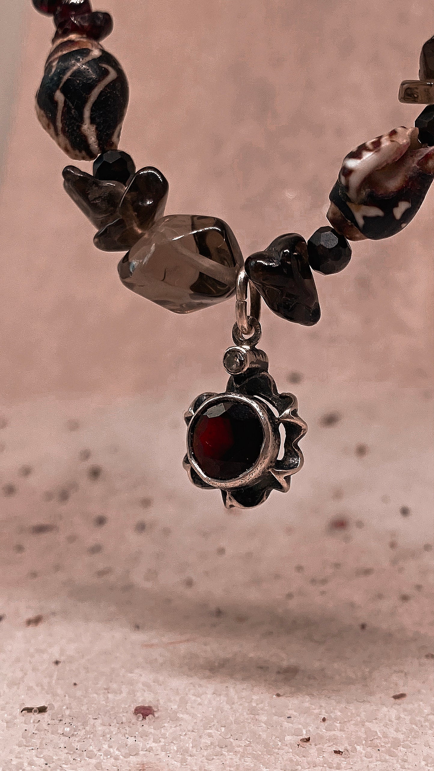 faceted garnet flower on textured garnet, seashell, glass